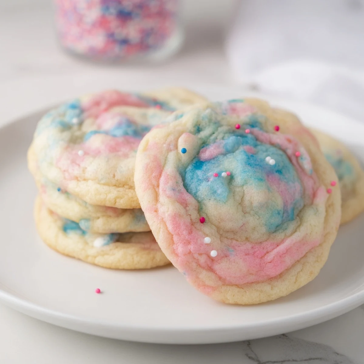 Fluffy cotton candy cookies topped with colorful sprinkles on a baking sheet.  