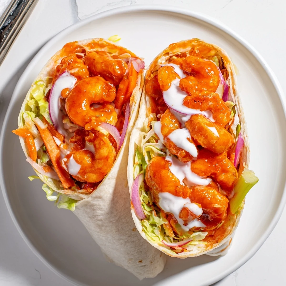 Fiery buffalo shrimp wraps bursting with colorful fresh vegetables and creamy ranch dressing.
