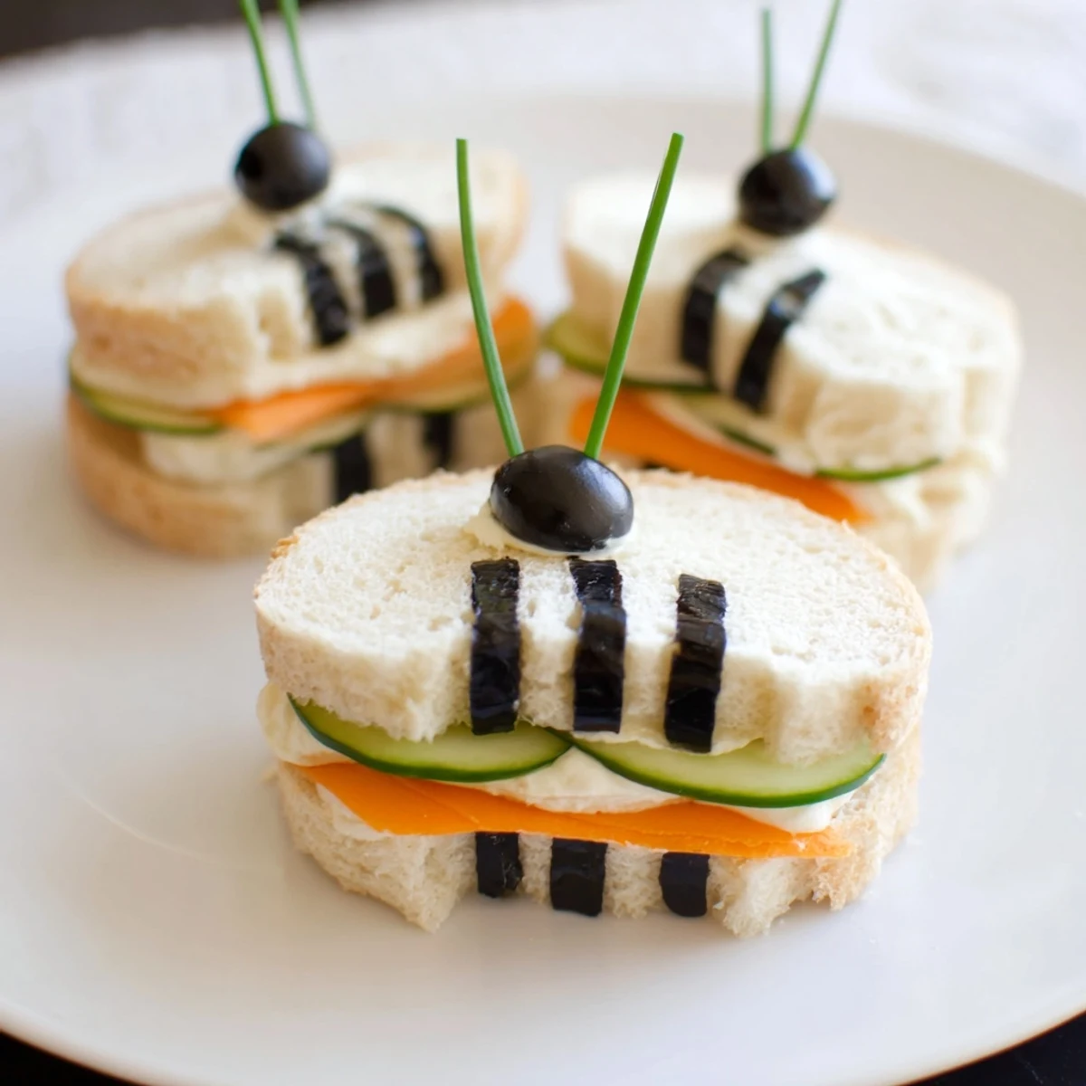 Bee sandwich cutouts: Adorable bee shaped sandwiches surrounded by fresh fruits and vegetables, perfect for a picnic.