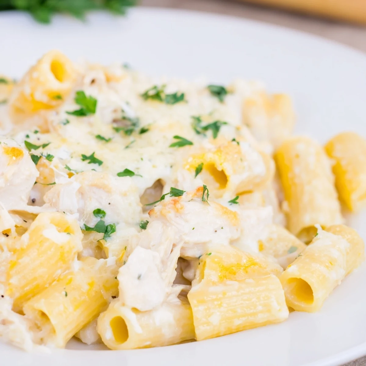 A close-up of a Chicken Alfredo Bake, showing tender chicken pieces in a rich, cheesy pasta.