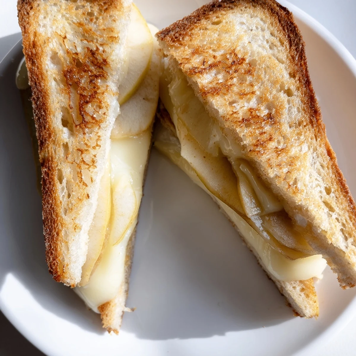 Golden grilled Brie and Apple Grilled Cheese with melted cheese oozing from toasted sourdough.