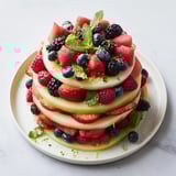 Bright summer fruit platter featuring juicy cantaloupe and berries arranged in an inviting presentation.