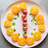 Bright orange slices neatly circle sweet grapes, forming the playful grape and orange slice clock face for a snack.