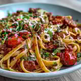 Steaming skillet of Italian Drunken Noodles with spicy sausage, blistered cherry tomatoes, onions, and garlic, tossed in a bold wine sauce.