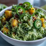 Vibrant guacamole with sweet mango chunks and spicy jalapeño, perfect for Cinco de Mayo parties or game day snacks.