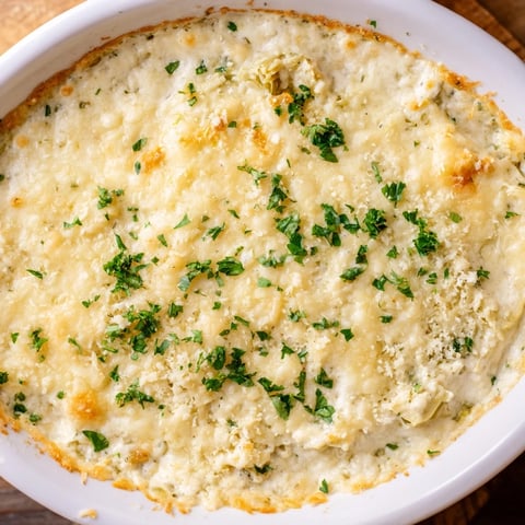 Golden, bubbly Baked Artichoke Dip with melted cheese, promising a warm, savory appetizer.