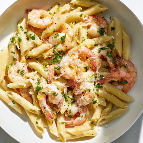 Golden garlic shrimp penne pasta, perfectly plated, with vibrant parsley as a garnish.
