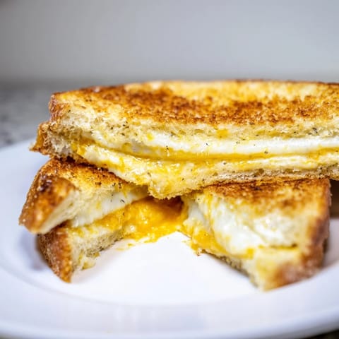 Crispy edges of Garlic Butter Mayo Grilled Cheese with melted cheddar, ready for a satisfying, warm bite.