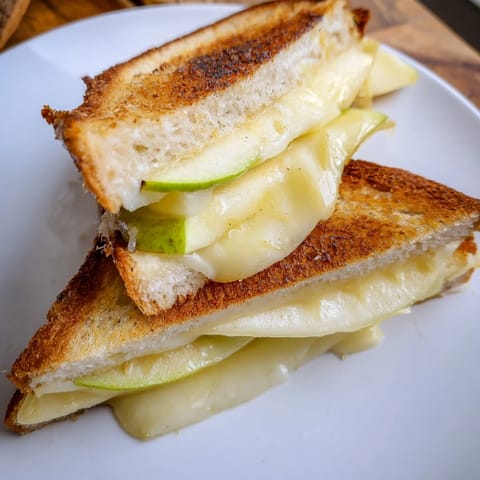 Perfectly browned Brie and Apple Grilled Cheese sandwich with crisp apple slices melting inside.