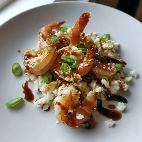 Close-up of perfectly cooked ginger garlic shrimp, glistening with a savory soy glaze atop cauliflower rice.