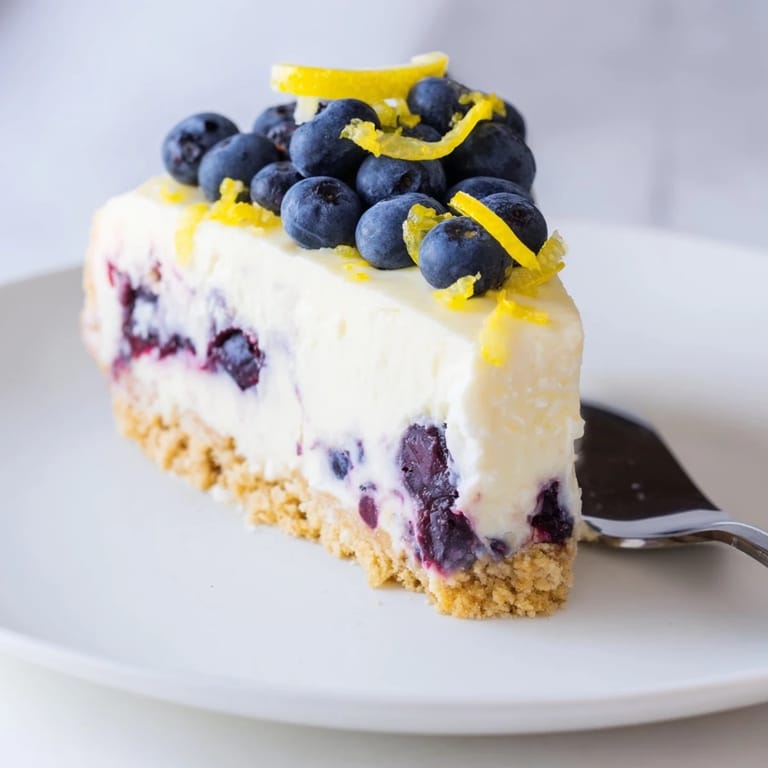 Sliced No-Bake Lemon Blueberry Cream Cake topped with zesty blueberries and lemon zest.
