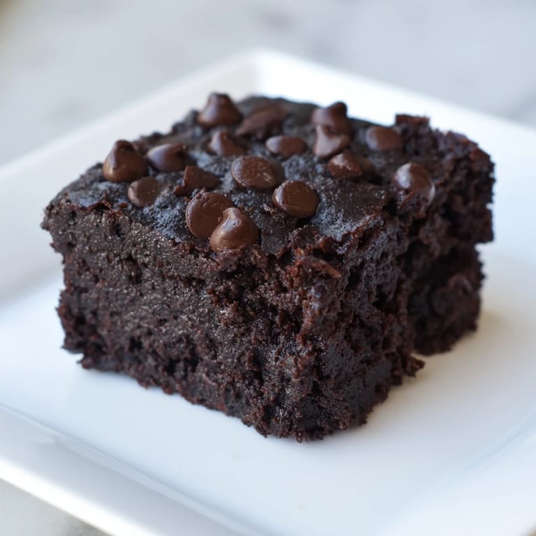 Close-up of decadent black bean brownies, cut into squares, showcasing a rich, dark chocolate texture.