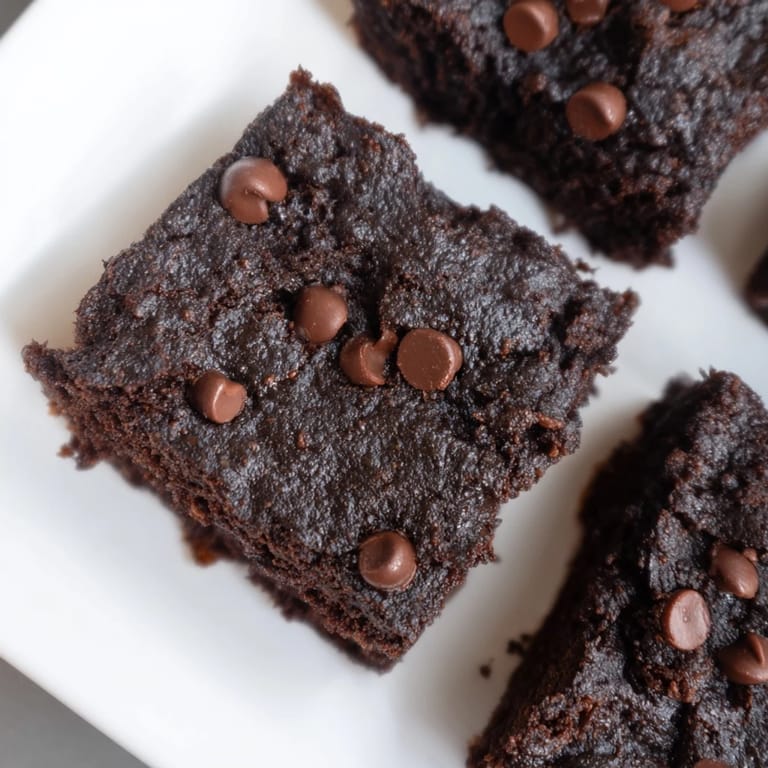 A plate of moist, gluten-free black bean brownies, perfect for a healthier chocolate dessert, deliciously tempting.