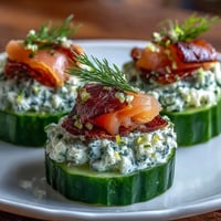 Smoked Salmon Cucumber Bites: Fresh cucumber rounds topped with herbed cream cheese and silky smoked salmon, garnished with dill. Ideal for elegant appetizers.